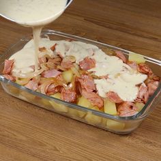 someone is pouring dressing on some food in a glass dish with potatoes and meats