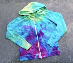 a blue and green tie - dyed hoodie laying on the ground