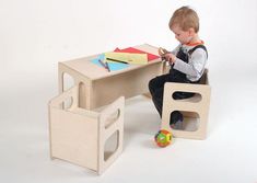 a young boy sitting at a wooden table with toys