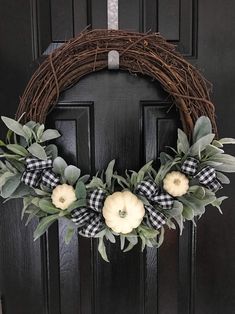 a wreath with white pumpkins and green leaves