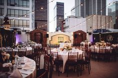 tables and chairs are set up in the middle of an outdoor patio with string lights