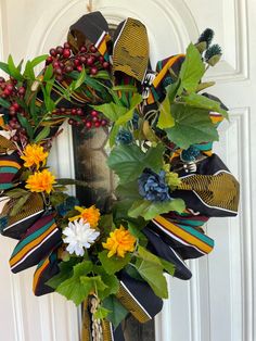 a wreath with flowers and leaves hanging on a door