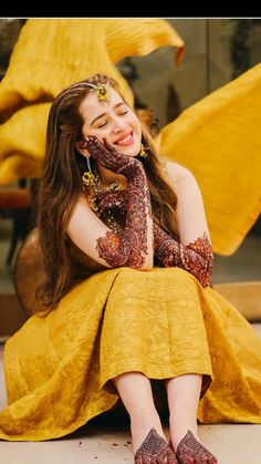 a woman sitting on the ground with her hands in her face and wearing henna