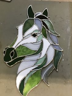 a stained glass horse head with green leaves on it