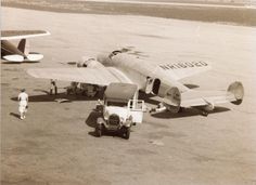 an old black and white photo of two planes on the tarmac with people standing around