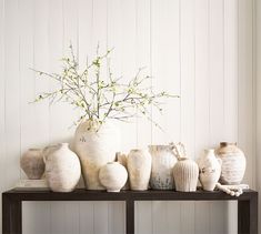 vases and flowers are sitting on a shelf in front of a white painted wall