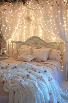 a bed with white sheets and lights on the headboard is decorated with pink flowers