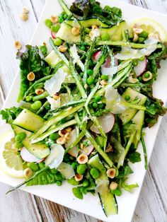 a white plate topped with green vegetables and lemon wedges