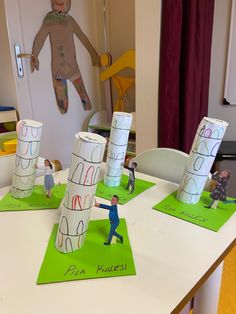 some paper cups are sitting on top of a table with children's drawings in them