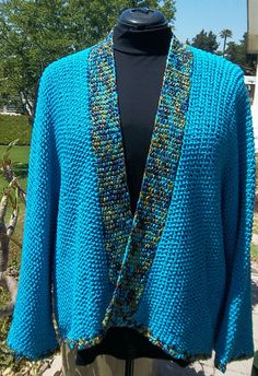 a blue knitted cardigan with beaded details on the front and back, sitting on a mannequin