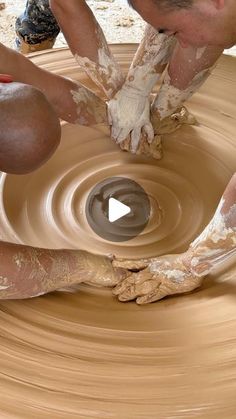 two men are making clay on a potter's wheel with their hands and feet