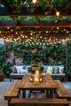 a wooden table with candles on it in front of some plants and lights hanging from the ceiling