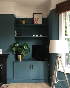 a living room with blue walls and a tv on top of a wooden cabinet next to a fireplace