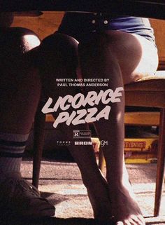 the legs of a person sitting in front of a table with a pizza on it