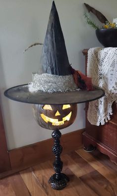 a table topped with a lit up pumpkin and a witches hat on top of it