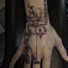 a person's hand with a tattoo on it and a cross in the middle