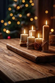 lit candles sit on a wooden table in front of a christmas tree