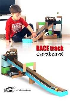 a young boy playing with a cardboard race track