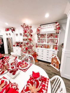 a white table topped with red and white plates covered in candy canes next to a christmas tree