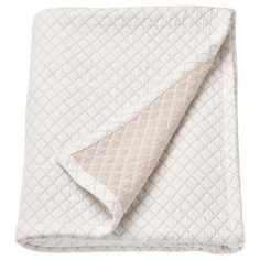 the white and beige quilted blanket is folded up