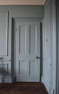 an empty room with white walls and wooden floors is pictured in this image, the door has been painted pale blue