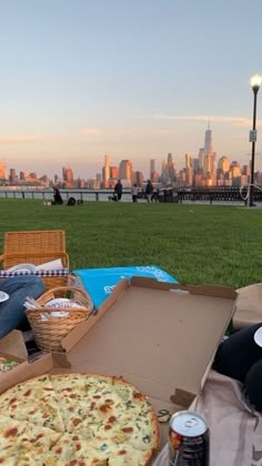 a person sitting on the grass with a pizza in front of them