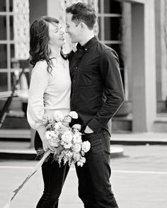 a man and woman standing next to each other with flowers in front of their faces