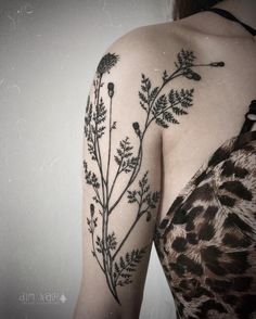 a woman's arm with flowers and birds tattoo on her left shoulder, next to a white wall