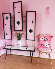 a room with pink walls and black frames on the wall, two chairs are next to each other