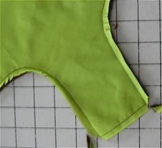 a green piece of cloth sitting on top of a white tile floor next to a ruler