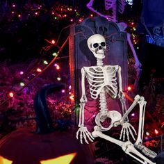 a skeleton sitting on top of a chair in front of a halloween tree with lights