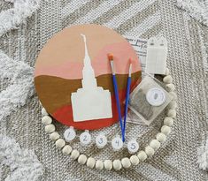 a table topped with beads and other items on top of a cloth covered floor next to a wooden bead necklace