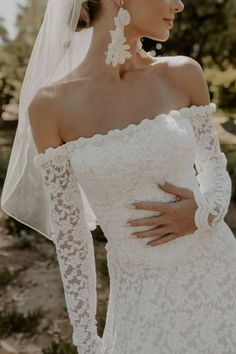 a woman wearing a wedding dress and veil with her hands on her hips, looking off to the side