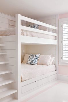 a white bunk bed sitting in a bedroom next to a window with shutters on both sides