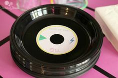 a black plastic plate with a green and yellow circle on the center sits on a pink tablecloth