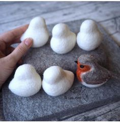 a felt bird sitting on top of a rock next to white wool balls in the shape of birds