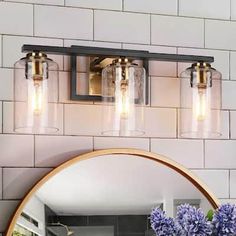 a bathroom vanity with two lights and a mirror on the wall next to blue flowers