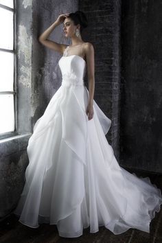 a woman in a white wedding dress leaning against a wall