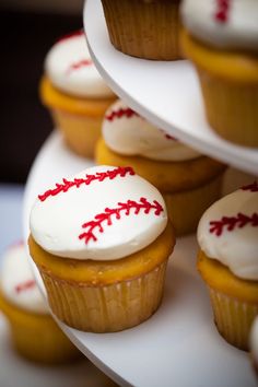 cupcakes with white frosting and red stitching on them sitting on a plate