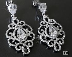 two pairs of diamond earrings on a black surface