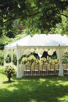 an outdoor tent with tables and chairs set up in the grass