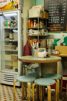 two stools sit at a small table in front of a refrigerated refrigerator