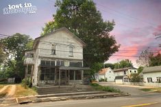 an old run down building sitting on the side of a road in front of some houses