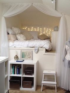 a white bed sitting under a canopy next to a book shelf filled with lots of books