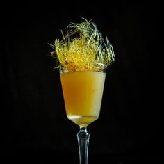 a glass filled with an orange drink and garnished with some yellow flakes