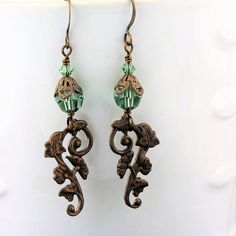 "An adorable new pair of crystal earrings with Swarovski crystals in a pretty pale emerald green, with a brass component with a gingko and ivy leaf pattern. These have a Victorian feel and are very lightweight! These one of a kind earrings measure 2 1/4\" and will arrive beautifully packaged. To see more jewelry and handmade beads, click here: https://www.etsy.com/shop/StoneDesignsbySheila?ref=hdr_shop_menu" Green Crystal Earrings For Jewelry Making, Handmade Green Crystal Metal Earrings, Green Dangle Jewelry With Bead Caps, Pierced Green Copper Earrings, Vintage Green Czech Glass Earrings, Green Copper Pierced Earrings, Elegant Green Copper Earrings, Green Bohemian Earrings With Bead Caps, Lampwork Bead Earrings