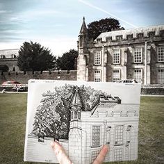 a person holding up a drawing in front of a building