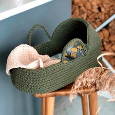 a crocheted basket sitting on top of a wooden chair next to a pile of wood