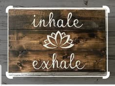 a wooden sign with the words inhale and an image of a flower on it