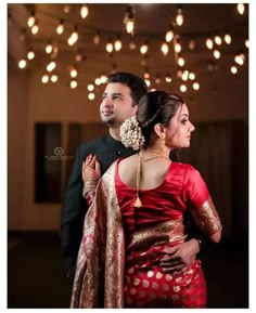 a man and woman standing next to each other in front of some lightbulbs